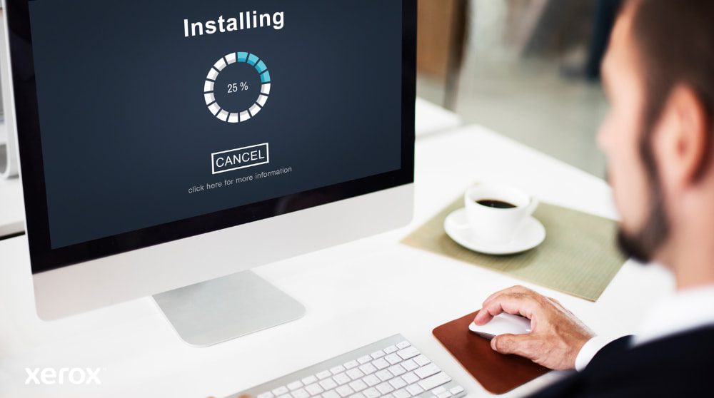 Xerox® Smart Start: installazione semplice e veloce Primo piano di un monitor di computer che mostra una barra di avanzamento "Installazione" al 25%, con la mano di una persona sul mouse del computer accanto a una tazza di caffè, a dimostrazione della semplice configurazione del software.