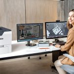 Stampante Xerox® VersaLink® C620 sul posto di lavoro Donna in un ufficio accanto alla stampante Xerox® VersaLink® C620