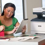 Stampante multifunzione Xerox® VersaLink® B415 sul posto di lavoro Due donne che utilizzano un tablet davanti a una stampante multifunzione Xerox® VersaLink® B415