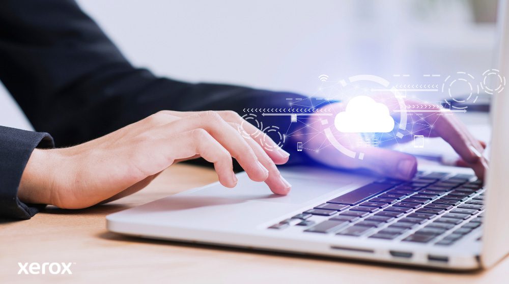 Xerox® Workplace Cloud e Suite: Connettività cloud Sono raffigurate le mani di una persona che digita sulla tastiera di un computer portatile, con un'icona luminosa a forma di nuvola e connessioni di rete sovrapposte all'immagine, a simboleggiare la connettività cloud e i flussi di lavoro digitali.